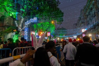 Kolkata, Batı Bengal, Hindistan - 26.12.2018: Aydınlatılmış ve dekore edilmiş park caddesinde coşkulu genç halk tarafından Noel kutlaması ve yıl sonu şenlik havası. Akşam gökyüzü arkaplanı.