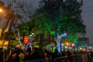 Kolkata, Batı Bengal, Hindistan - 26.12.2018: Aydınlatılmış ve dekore edilmiş park caddesinde coşkulu genç halk tarafından Noel kutlaması ve yıl sonu şenlik havası. Akşam gökyüzü arkaplanı.