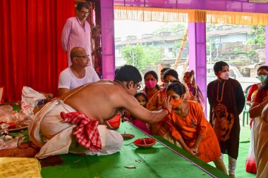 Howrah, Batı Bengal, Hindistan - 14 Ekim 2021: Hindu Purohit, Tanrıça Durga 'ya ibadet etmek için tanrıça Durga' ya itme sırasında dindarların alınlarına kutsal tilak takıyor..
