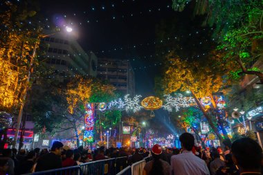 Kolkata, Batı Bengal, Hindistan - 25.12.2018: Aydınlatılmış ve dekore edilmiş park caddesinde coşkulu genç halk tarafından Noel kutlaması ve yıl sonu şenlik havası. Akşam gökyüzü arkaplanı.