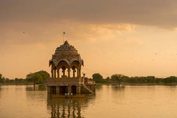 Chhatris and shrines of hindu Gods and goddesses at Gadisar lake, Jaisalmer, Rajasthan, India with reflection on water. Indo-Islamic architecture , sun set and colorful clouds with Gadisar lake.