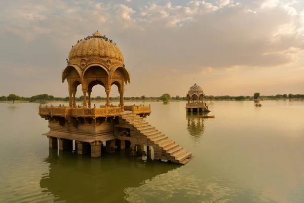 Chhatris and shrines of hindu Gods and goddesses at Gadisar lake, Jaisalmer, Rajasthan, India with reflection on water. Indo-Islamic architecture , sun set and colorful clouds with Gadisar lake.