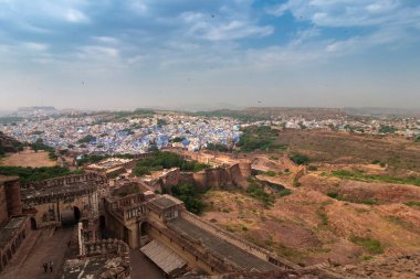 Top view of Mehrangarh fort with distant view of blue city Jodhpur, Rajasthan, India. Blue sky with white clouds in the background. Historical Fort is UNESCO world heritage site