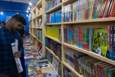 Kolkata, Batı Bengal, Hindistan - 2 Şubat 2020: Elinde kitap fuarı haritası olan genç adam, Kolkata Kitap Fuarı 'ndaki bir kitapçıda sergilenmekte olan kitap kapaklarını okuyor. En büyük kitap fuarı.