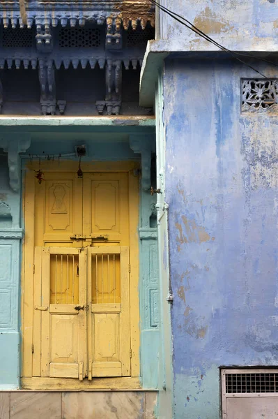 Traditional yellow wooden door and blue coloured house of Jodhpur city, Rajsthan, India. Historically, Hindu Brahmins used to paint their houses in blue for being upper caste, the tradition follows.