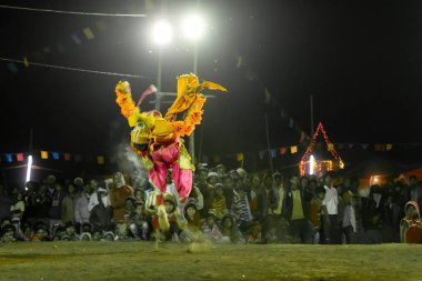 Purulia, Batı Bengal, Hindistan - 23 Aralık 2015: Purulia 'nın Chhau dansı. UNESCO 'nun İnsanlığın Soyut Kültürel Mirası. Akrobatik erkek dansçı havada atlıyor, köylüler izliyor..