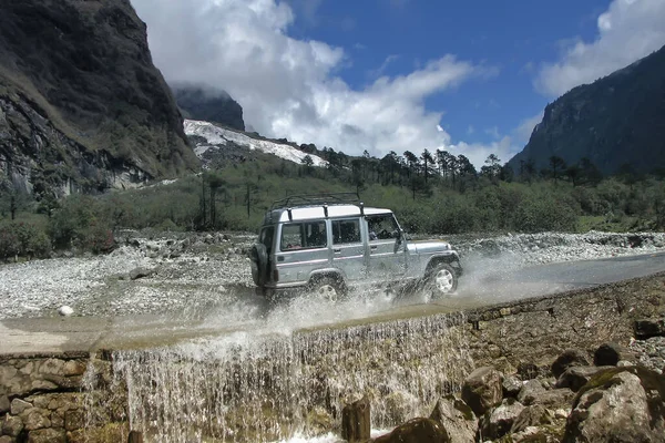 stock image Tourist car crossing fountain at Yumthang Valley or Sikkim Valley of Flowers sanctuary, Himalayan mountains, North Sikkim, India. Shingba Rhododendron Sanctuary. Favourite tourist spot of Sikkim.