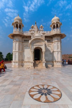 Jodhpur, Rajasthan, Hindistan - 20.10.2019: Jaswant Thada Cenotaph 'ın güzel mimarisini canlandıran ziyaretçiler. Makrana mermeri güneş tarafından aydınlatıldığında sıcak parıltı yayar. Mavi gökyüzü arkaplanı.