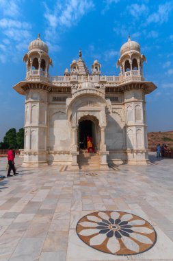 Jodhpur, Rajasthan, Hindistan - 20.10.2019: Jaswant Thada Cenotaph 'ın güzel mimarisini canlandıran ziyaretçiler. Makrana mermeri güneş tarafından aydınlatıldığında sıcak parıltı yayar. Mavi gökyüzü arkaplanı.