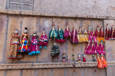 Jaisalmer, Rajasthan, Hindistan - 16 Ekim 2019: Patwon Ki Haveli yakınlarında duvarda asılı geleneksel Rajasthani Raja Rani bebekleri. Bunlar Jaisalmer 'e seyahat eden turistlerin favorisi..