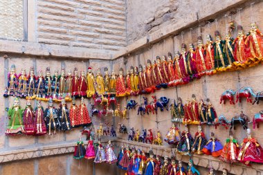 Jaisalmer, Rajasthan, Hindistan - 16 Ekim 2019: Patwon Ki Haveli yakınlarında duvarda asılı geleneksel Rajasthani Raja Rani bebekleri. Bunlar Jaisalmer 'e seyahat eden turistlerin favorisi..