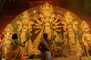 Howrah, Batı Bengal, Hindistan - 3 Ekim 2022: Hindu rahipler kabuk kabuğuyla tanrıça Durga 'ya tapıyorlar. Ashtami puja aarati - kutsal Durga Puja ritüeli - Hinduizm festivali geceleri gerçekleştiriliyor.