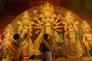 Howrah, Batı Bengal, Hindistan - 3 Ekim 2022: Hindu rahipler kabuk kabuğuyla tanrıça Durga 'ya tapıyorlar. Ashtami puja aarati - kutsal Durga Puja ritüeli - Hinduizm festivali geceleri gerçekleştiriliyor.