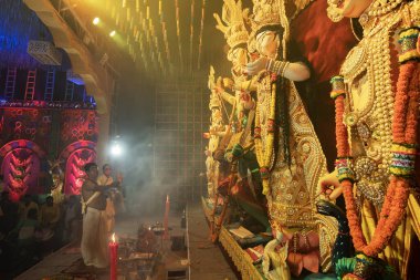 Howrah, Batı Bengal, Hindistan - 3 Ekim 2022: Hindu rahipler Tanrıça Durga 'ya aynayla tapıyorlar ki Tanrıça elbisesini görebilsin. Ashtami puja aarati - Durga Puja ritüeli - Hinduizm festivali.