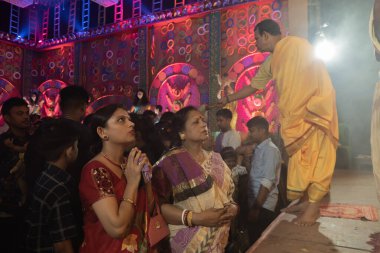 Howrah, Batı Bengal, Hindistan - 3 Ekim 2022: Hindu Bengali sarisi Durga Puja pandalı içinde tanrıça Durga 'ya dua eden kadınlara giydirildi. Gece Ashtami puja aarati. Hinduizm 'in en büyük fetsivası.