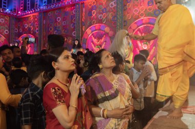 Howrah, Batı Bengal, Hindistan - 3 Ekim 2022: Hindu Bengali sarili kadın, Durga Puja Pandali 'nin içinde elleri bağlı tanrıça Durga' ya dua ediyor. Hinduizm 'in en büyük fetsivası.