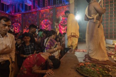 Howrah, Batı Bengal, Hindistan - 3 Ekim 2022: Hindu Bengali sarisi Durga Puja pandalı içinde tanrıça Durga 'ya dua eden kadınlara giydirildi. Gece Ashtami puja aarati. Hinduizm 'in en büyük fetsivası.