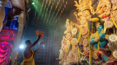 Howrah, Batı Bengal, Hindistan - 5 Ekim 2022: Hindu Purohit, Durga Puja pandalının içinde, geleneksel Hindu kadın elbisesi olan Sari ile tanrıça Durga 'ya tapıyor. Durga Puja ritüeli.