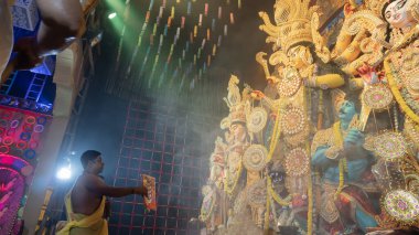 Howrah, Batı Bengal, Hindistan - 5 Ekim 2022: Hindu Purohit, Durga Puja pandalının içinde, geleneksel Hindu kadın elbisesi olan Sari ile tanrıça Durga 'ya tapıyor. Durga Puja ritüeli.