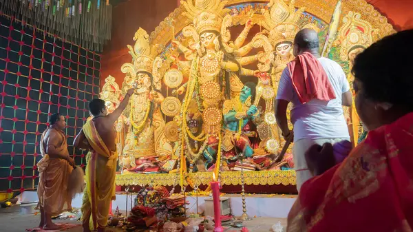 Howrah, Batı Bengal, Hindistan - 5 Ekim 2022: Hindu Purohit 'ler Durga' ya tapıyor, büyük bir yelpazeyle onu Durga Puja pandalının içinde havalandırıyor. Durga Puja ayini. Hinduizm Festivali.