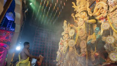 Howrah, Batı Bengal, Hindistan - 5 Ekim 2022: Hindu Purohit, Durga Puja pandalının içinde, geleneksel Hindu kadın elbisesi olan Sari ile tanrıça Durga 'ya tapıyor. Durga Puja ritüeli.