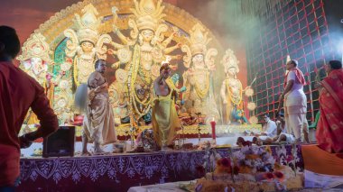 Howrah, Batı Bengal, Hindistan - 5 Ekim 2022: Dhaakis Tanrıça Durga 'ya tapmak için dhaaks çalarken, Tanrıça' ya Vog, kutsal tatlı yiyecekler sunuluyor. Puja pandalında kutsal bir Durga Puja ritüeli..