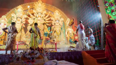 Howrah, Batı Bengal, Hindistan - 5 Ekim 2022: Hindu Purohits Tanrıça Durga için kutsal tatlı yiyecekler sunarken Durga puja pandalının içinde kutsal dumanla kaplı.