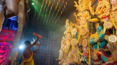 Howrah, Batı Bengal, Hindistan - 5 Ekim 2022: Hindu Purohit, Durga Puja pandalının içinde, geleneksel Hindu kadın elbisesi olan Sari ile tanrıça Durga 'ya tapıyor. Durga Puja ritüeli.