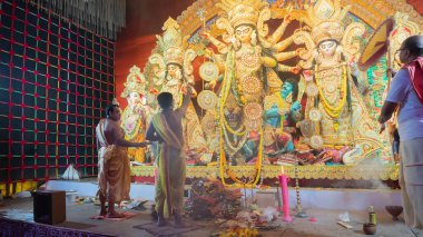 Howrah, Batı Bengal, Hindistan - 5 Ekim 2022: Hindu Purohit 'ler Durga' ya tapıyor, büyük bir yelpazeyle onu Durga Puja pandalının içinde havalandırıyor. Durga Puja ayini. Hinduizm Festivali.