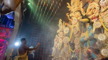 Howrah, Batı Bengal, Hindistan - 5 Ekim 2022: Hindu Purohit, Durga Puja pandalının içinde, geleneksel Hindu kadın elbisesi olan Sari ile tanrıça Durga 'ya tapıyor. Durga Puja ritüeli.