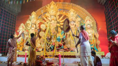 Howrah, Batı Bengal, Hindistan - 5 Ekim 2022: Hindu Purohit 'ler Durga' ya tapıyor, büyük bir yelpazeyle onu Durga Puja pandalının içinde havalandırıyor. Durga Puja ayini. Hinduizm Festivali.