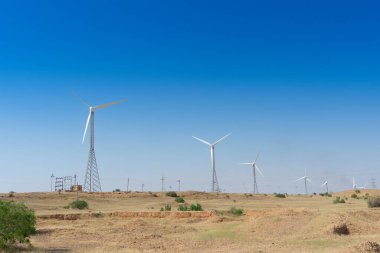 Mavi çöl gökyüzü ve elektrik santralleri yerel insanlar tarafından tüketilmek üzere alternatif çevre dostu yeşil enerji üretiyorlar. Thar Çölü, Rajasthan, Hindistan. Çevre dostu güç kaynağı.