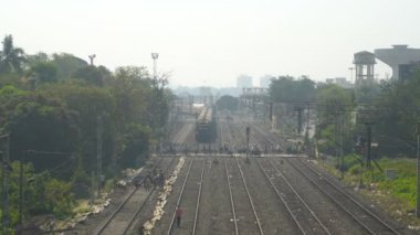 Bir yolcu treni, Howrah, West Bengal, Hindistan ufkundan geçerken yaya geçidi düzleminden geçiyor. Demiryolu işçileri raylarda çalışıyor. Hint demiryolu manzarası.
