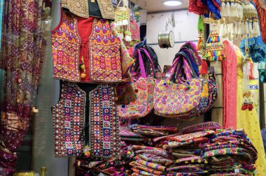 Jodhpur, Rajasthan, Hindistan - 15.10.2019: Rajasthani kadınlarının giysileri ve renkli kadın çantaları ünlü Sardar Market ve Ghanta ghar saat kulesi pazarında satışa sunuluyor. Turistler için ünlü bir yer..