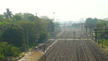 Bir yolcu treni, Howrah, West Bengal, Hindistan ufkundan geçerken yaya geçidi düzleminden geçiyor. Demiryolu işçileri raylarda çalışıyor. Hint demiryolu manzarası.