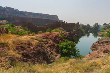 Rao Jodha çölündeki Jodhpur, Hindistan 'dan Mehrangarh kalesinin manzarası. Önde bir göl, arkada Mehrangarh kalesi ve çöl parkının kayalık manzarası..