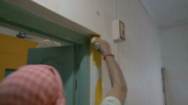 Eski evin soluk duvarını boyamak için fırça kullanan bir ressam. Howrah, Batı Bengal, Hindistan