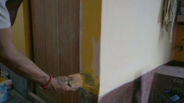 Eski evin soluk duvarını boyamak için fırça kullanan bir ressam. Howrah, Batı Bengal, Hindistan