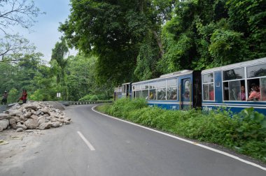 Darjeeling,West Bengal,India - 10th August 2023 : Himalayan road being constructed by workers while Diesel Toy train passing through jungle beside. Darjeeling Himalayan Railway, narrow gauge railway. clipart