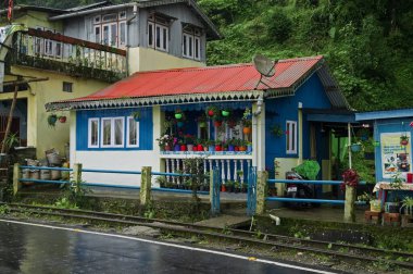 Darjeeling, Batı Bengal, Hindistan - 10 Ağustos 2023: Güzel renkli köy ve Himalaya dağlarından geçen beton yol, yemyeşil orman. Darjeeling 'de musonun doğal güzelliği.