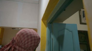 Howrah, Batı Bengal, Hindistan - 06.08.2023: Hintli ressam eski evin soluk duvarını boyamak için fırça kullanıyor. Renkli ev duvarları için iç mekan boyama.