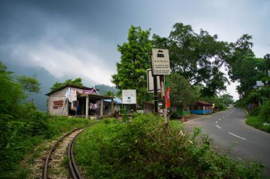 Darjeeling, Batı Bengal, Hindistan - 10 Ağustos 2023: Darjeeling 'deki yol kenarı köyü. Himalaya dağları ve arkada muson bulutları. Oyuncak tren hattı, Darjeeling Himalaya Demiryolu.