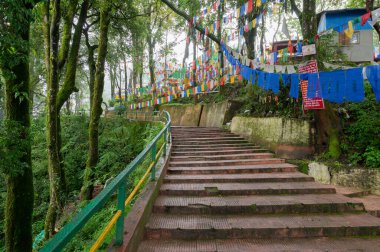 Darjeeling, Batı Bengal, Hindistan-11.08.2023: Ormandaki merdivenlerde bayraklar, Mahakal Tapınağı veya Mahakal Mandir yolu, Hindu dinlerinin bir karışımı olan Shiva 'ya adanmış Hindu tapınağı..