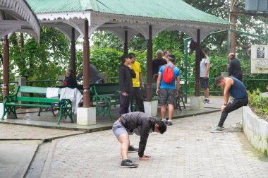 Darjeeling, Batı Bengal, Hindistan - 11.08.2023: Sağlık bilinci olan genç erkekler Darjeeling alışveriş merkezinde sisli bir sabahta sohbet ediyor ve egzersiz yapıyorlar. Şık spor kıyafetleri, genç Himalaya yaşam tarzı..