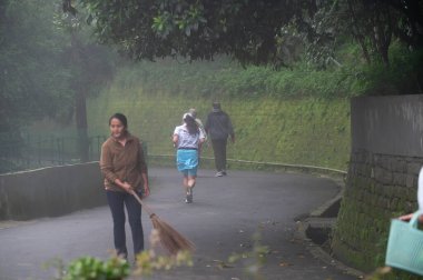 Darjeeling, Batı Bengal, Hindistan - 11.08.2023: Darjeeling alışveriş merkezinde sisli bir sabahta koşan sağlık bilinci olan genç kadın. Spor giyimli, genç Himalaya yaşam tarzı.