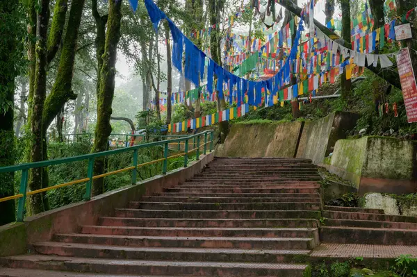 stock image Darjeeling,West Bengal,India-11.08.2023: Flags on stair cases in forest,way to Mahakal Temple or Mahakal Mandir, Hindu temple dedicated to God Shiva, an amalgamation of Hindu and Buddhist religions.