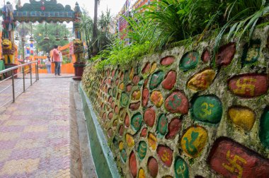 Colourful Hindu religious symbols painted on colourful stones, sacred symbols of traditional Hinduism. The walls at side of way to Mahakal Temple, ancient Hindu temple at Darjeeling,West Bengal,India. clipart