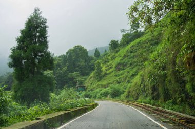 Himalaya dağlarından geçen beton yol ve yemyeşil orman. Darjeeling, Batı Bengal, Hindistan 'da musonun doğal güzelliği..