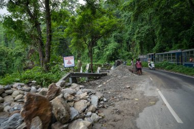 Darjeeling,West Bengal,India - 10th August 2023 : Himalayan road being constructed by workers while Diesel Toy train passing through jungle beside. Darjeeling Himalayan Railway, narrow gauge railway. clipart