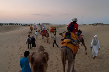 Thar Çölü, Rajassthan, Hindistan - 15 Ekim 2019: Thar Çölü 'nün kum tepelerinde deveye binen turistler. Deve sürmek burayı ziyaret eden tüm turistler arasında favori bir etkinliktir.,